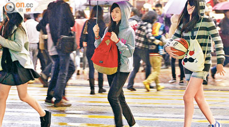 寒風冷雨，穿短褲短裙的少女急步過路。（伍鎮業攝）