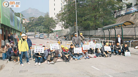 工人手持標語走出馬路靜坐。（黃智康攝）