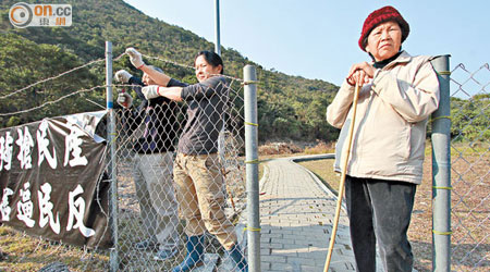 一名年長女村民持杖守在鐵閘前，周一至周五禁止閒雜人等通過。（陳錦輝攝）