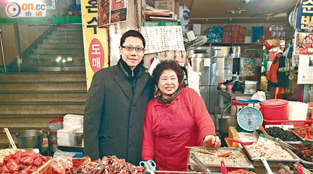 黃傑龍（左）試食醃生蟹，同女店主合照留念。（受訪者提供）