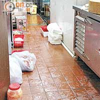 廚房地面濕滑，部分食材隨意擺放地上，衞生情況惡劣。