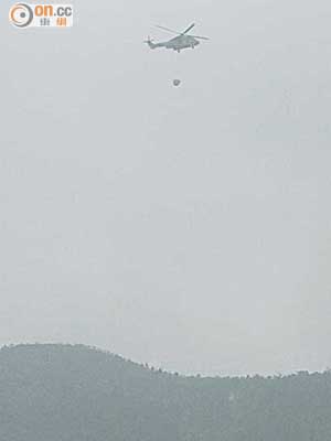 直升機昨晨投擲水彈撲救八仙嶺山火。（梁卓明攝）