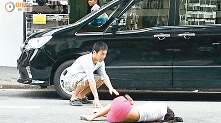墮樓印度婦受傷倒臥馬路，途人在旁安慰。（讀者提供）