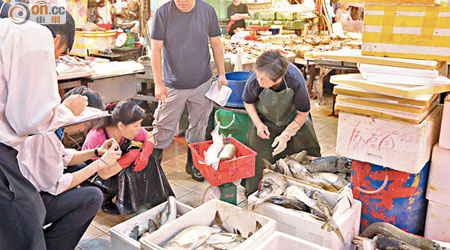 魚檔東主與食環署人員點算損失情況。（林珮淇攝）