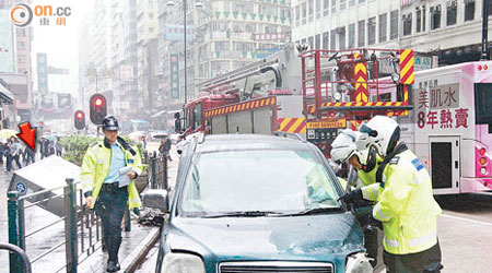 私家車失控撞冧電箱（箭嘴示）後，被警員推到路邊搜查。（曾志恒攝）