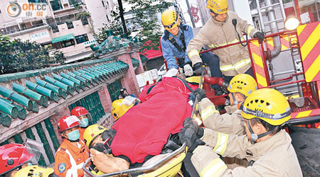 消防員合力將傷者救下送院。（賴南秋攝）