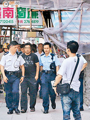 企圖引爆石油氣的南亞漢（左二）隨警員到警署。（伍啟衞攝）
