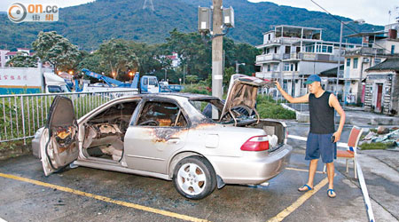 麥展鴻查看被縱火私家車的損毀情況。（楊偉嶽攝）