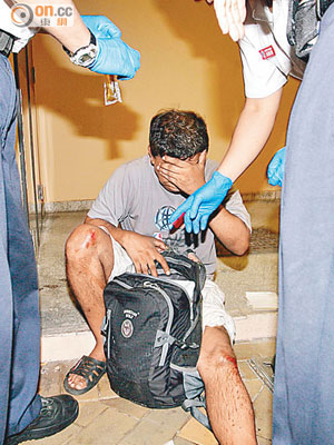 受傷暈倒的南亞漢坐在地上協助警員調查。（吳建明攝）