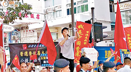保衞香港運動成員傅振中（持咪者）在修頓球場附近舉着五星旗及香港特區區旗，高呼支持白皮書等口號。