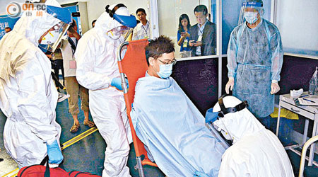 全副裝備的醫護人員，將疑似感染伊波拉病毒的入境旅客送院。