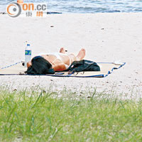 不少泳客愛在沙灘曬太陽，與草堆為鄰。