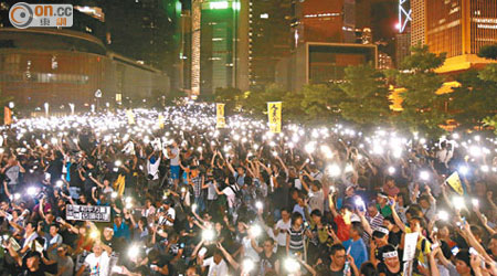 包圍政總<br>部分示威者高舉發光的手機，猶如在政總外燃起點點燭光。（黃永俊攝）