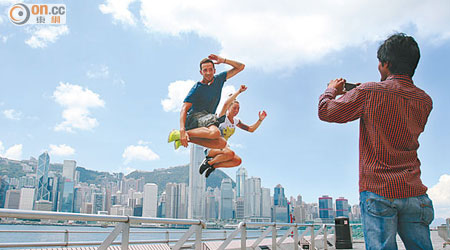 天朗氣清的維港，遊人拍攝「跳躍」照。（洪業銘攝）