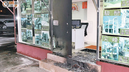 遭縱火地產代理店的玻璃門爆裂，碎片遍地。（楊日權攝）