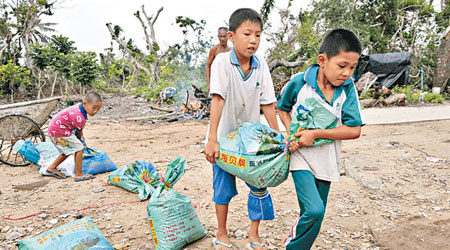 文昌翁田鎮受颱風吹襲，當地小孩將沙包搬回家防災。（中新社圖片）
