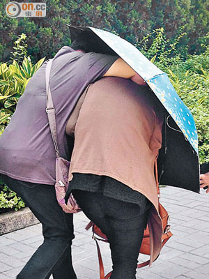 女被告黃燕紅（右）離庭時由朋友持傘掩護離開。