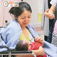 女住客手抱嬰兒送院治療，驚慌失措。（曾紹良攝）