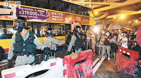 數名落單的防暴警員反被示威者包圍，須臨時以水馬及遺棄巴士作防禦自保。（袁志豪攝）