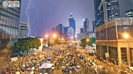 金鐘<br>昨日傍晚港島區突然雷雨交加，金鐘夏慤道的佔中集會人士冒雨留守。（潘思維攝）