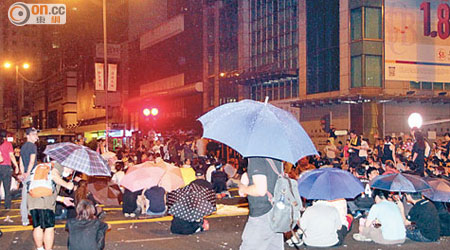 彌敦道有人從高處灑水，示威者紛舉傘「避雨」。（葉嘉文攝）