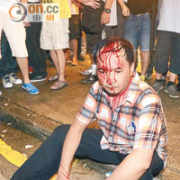 示威衝突中有人被打到血流披臉，呆坐地上等候救援。（何力棋攝）