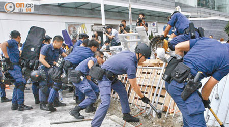 警員以大鐵錘把示威者用以加固路障的水泥敲碎。