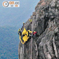 數名攀山者昨早攀上獅子山上的獅子頭峭壁，準備掛上巨型黃色直幡。（讀者提供）