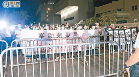 百多名示威者拉起橫額在壹傳媒總部外抗議，並開着電筒。（高潤榮攝）