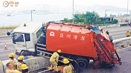 垃圾車騎在石壆漏油，消防員在旁戒備。（林景輝攝）