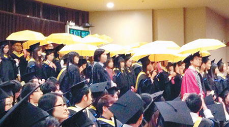 浸大昨早舉行畢業典禮時，約十名學生在台下舉起黃雨傘。（互聯網圖片）