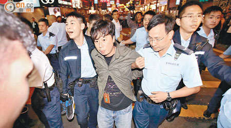涉嫌襲警的《蘋果日報》攝影記者被警員帶走調查。