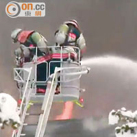 消防人員出動雲梯向大火中旅館房舍噴水灌救。