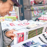 北京市民關注當地報刊昨日有關周永康被開除黨籍的報道。（中新社圖片）