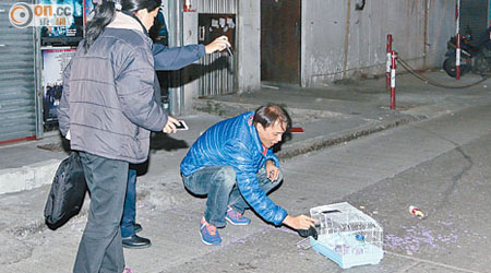 警員檢查被擲落街的寵物籠。