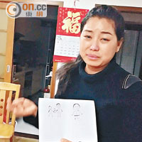 梁妻憶亡夫落淚，展示女兒畫給其父親的畫作。（本報深圳傳真）