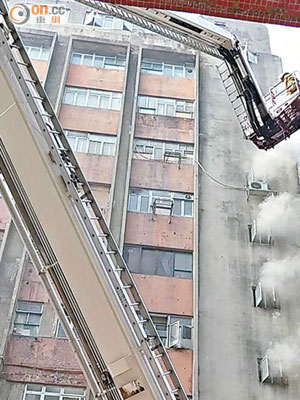 大廈冒出濃煙，消防架起升降台射水灌救。（讀者提供）