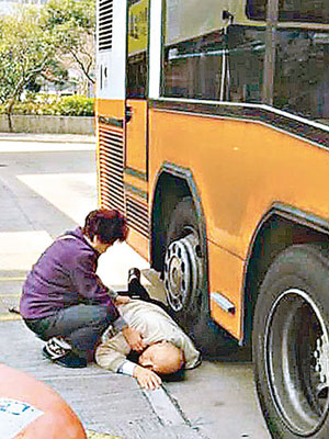老翁外套被巴士車輪壓住被困，其妻子在旁安撫。（互聯網圖片）