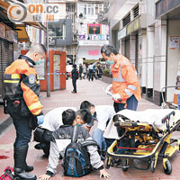 被跳樓青年壓傷的途人，在現場由救護員急救。（梁卓明攝）
