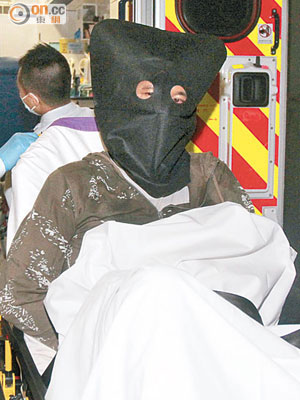 疑犯被綁在擔架床上送上救護車。（李國健攝）