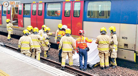 消防員在列車底將死者遺體及殘肢抬出。（李惠攝）
