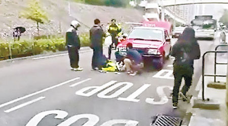 警員倒於的士車前，手掌被車輪壓着，途人正協助救。（互聯網圖片）