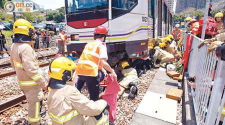消防員拯救被捲入列車底的攝影師。（黃君堡攝）