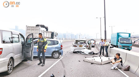 跌落馬路的床褥引致三車相撞，七人車司機受傷坐在路旁。（馬竟峯攝）