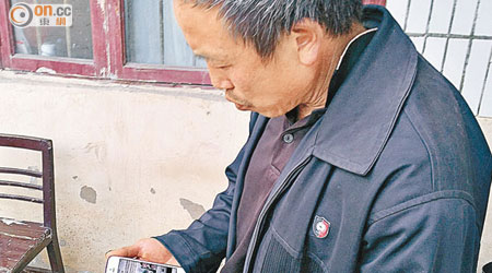 毛小兵父親在其他村民手機觀看綁架案消息。（本報貴州傳真）