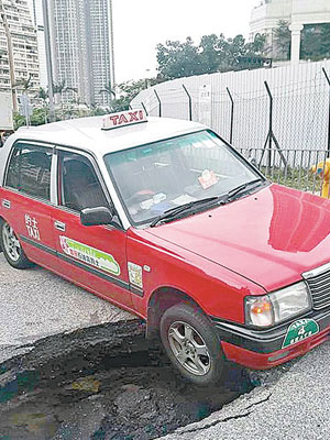 的士右前輪陷入路面洞中。（FB小心駕駛群組圖片）