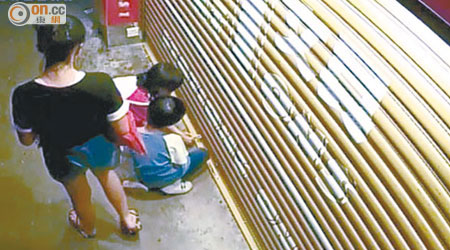三名男女童在文具店閘門外疑圖弄開密碼鎖。（讀者提供）