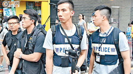 手持攝影機的搜證小隊成員和穿藍色背心的傳媒聯絡員現身遊行。（羅錦鴻攝）
