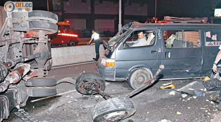 密斗貨車撞防撞欄翻側，前輪車軸甩脫，尾隨客貨車煞掣不及撼作一團，司機被困。（王偉安攝）