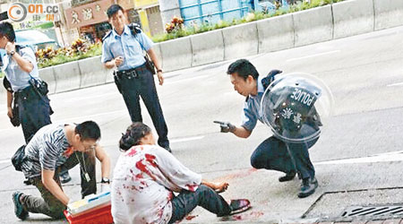 重傷婦人跌坐路邊，上衣染血，警員趕抵調查。（讀者提供圖片） 